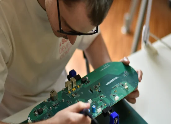 En mann med briller jobber manuelt med maskinvare ved hjelp av verktøy som loddebolt