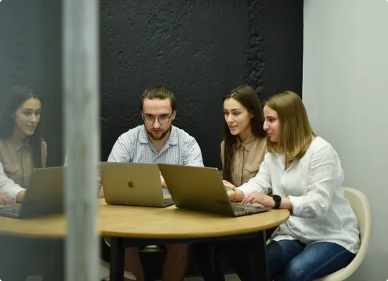 En mann og to kvinner bruker en bærbar datamaskin for produktvedlikehold og støtte