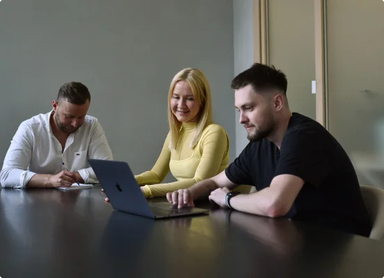 Drei Einzelpersonen arbeiten mit einem MacBook-Laptop und bieten Experten-IT-Beratungsdienste an