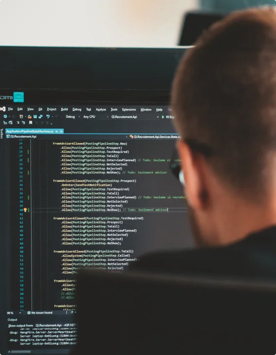 En IT-mann iført en svart skjorte, står overfor en åpen dataskjerm og produserer skreddersydde programvareutviklingsprodukter