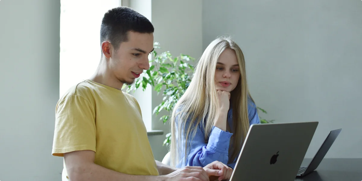 En kvinne og en mann ser på en bærbar dataskjerm med LANARS programvareteknologier og programmeringsteam